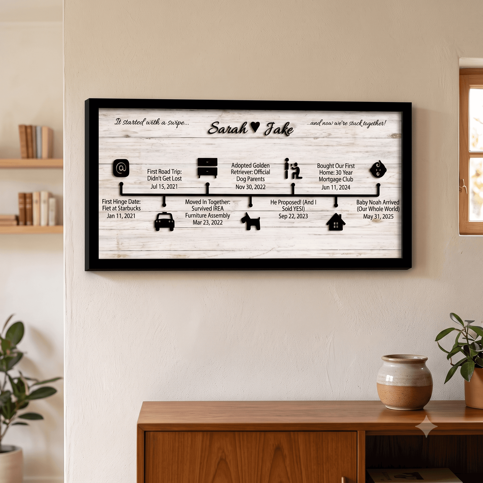 Black-framed love story wood sign with laser-cut raised icons on a whitewashed MDF background